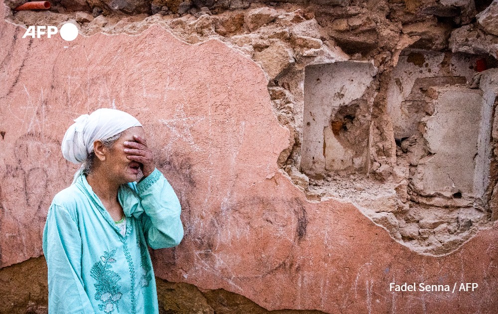 Woman reacts standing infront of her earthquake-damaged house